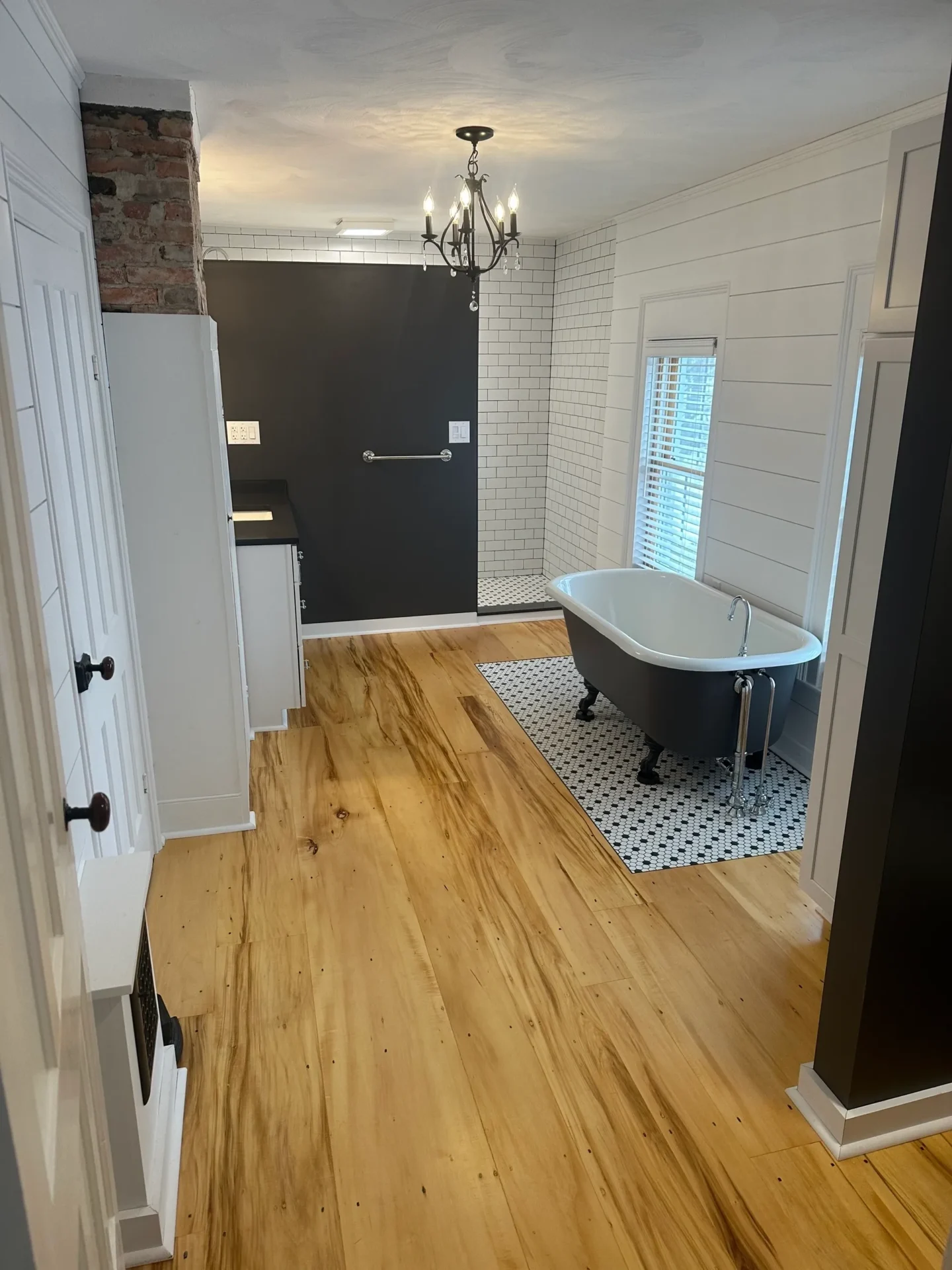A bathroom with hardwood floors and a bathtub.